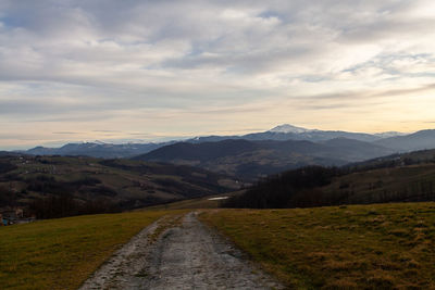 Road leading towards mountains against sky