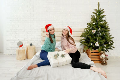 Young woman sitting by christmas tree