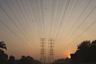 Low angle view of silhouette electricity pylon against sky during sunset