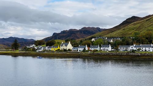 Houses by river against sky