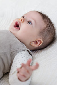 Portrait of cute baby lying on bed at home