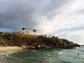 Built structure on beach against cloudy sky