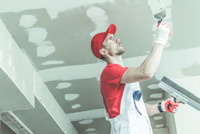 Low angle view of manual worker painting wall