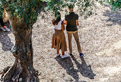 Rear view of people walking on street amidst trees