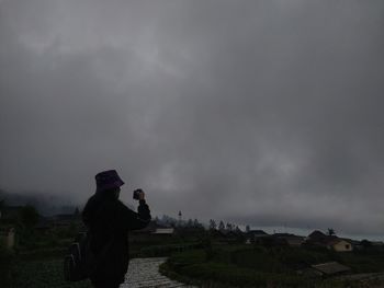 Rear view of man photographing against sky