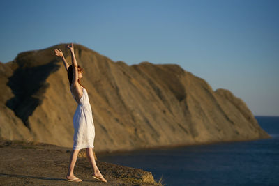 Woman standing by sea against clear sky