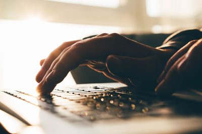 Cropped hands of woman using laptop