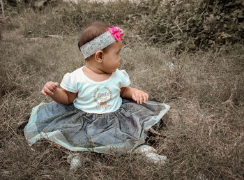 High angle view of cute baby girl sitting on land