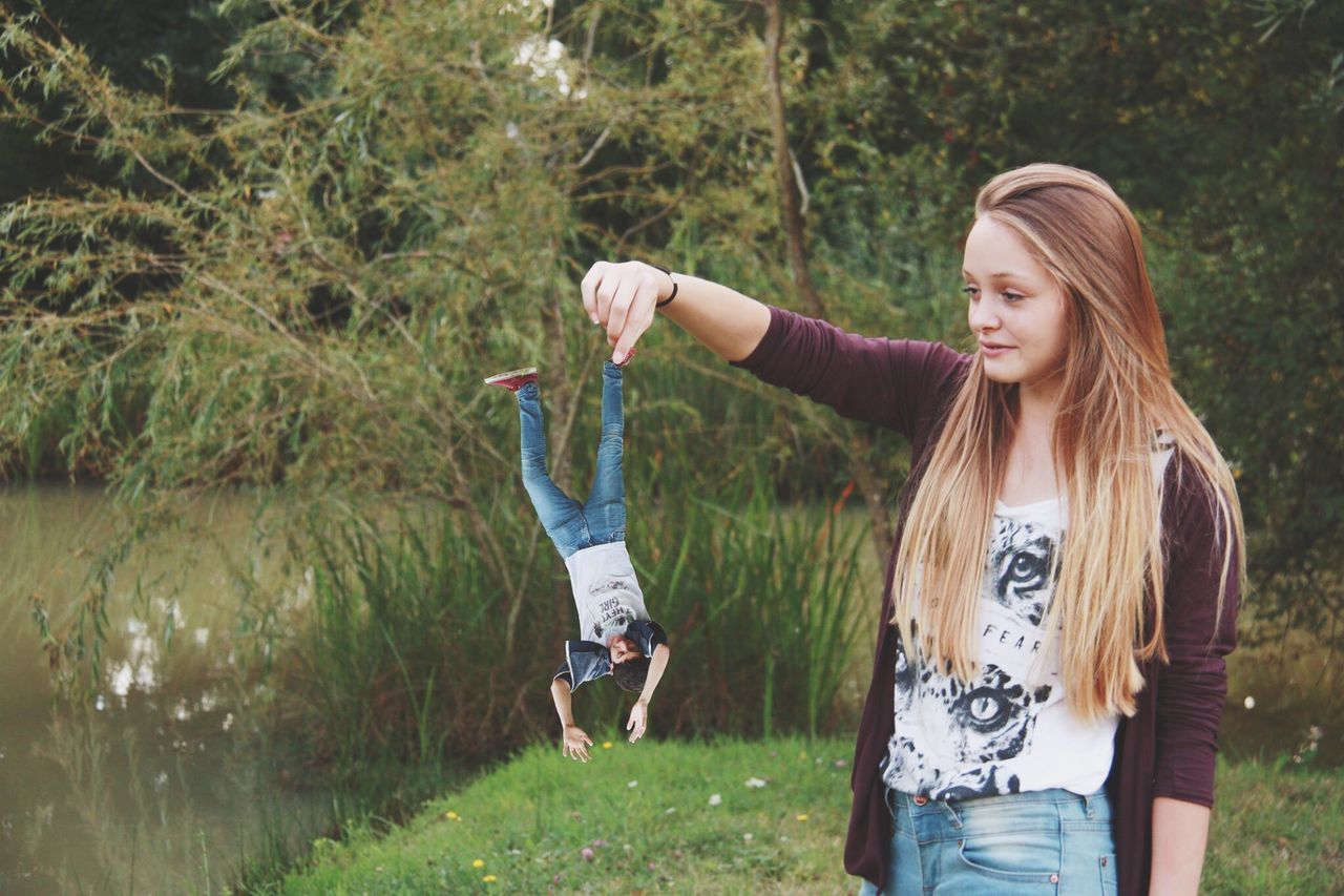 lifestyles, casual clothing, leisure activity, young adult, person, standing, young women, three quarter length, full length, tree, smiling, long hair, grass, happiness, front view, nature, looking at camera, outdoors