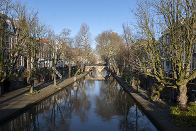 Canal amidst trees against sky