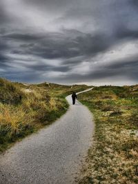 Man walking on road against sky