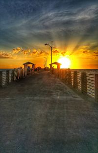 Street by sea against sky during sunset