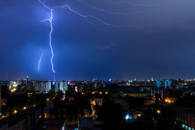 Lightning over illuminated buildings in city at night