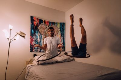 Digital composite image of magician coming out from hula hoop over bed