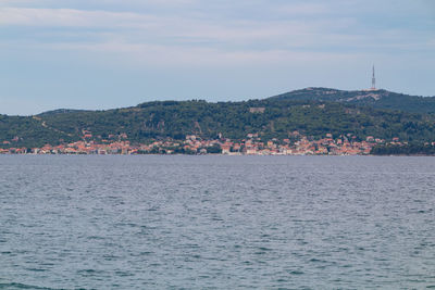 Scenic view of sea by town against sky
