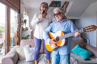 Full length of man playing guitar on sofa