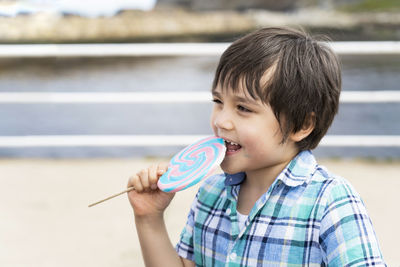 Close-up of cute boy eating lollipop outdoors