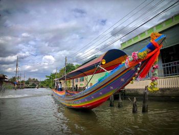 Multi colored boats moored on river against sky