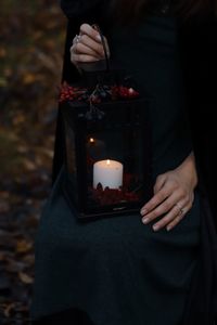 Midsection of woman holding illuminated candles