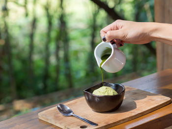 Cropped hand of woman pouring sauce on food at table