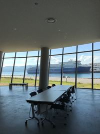 Chair by sea against sky seen through window