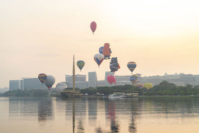 Hot air balloon flying over lake against sky during sunset