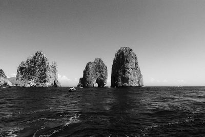 Rock formations in sea against clear sky