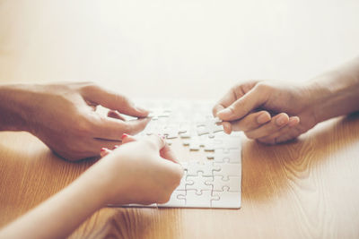 Midsection of couple playing with hands on table