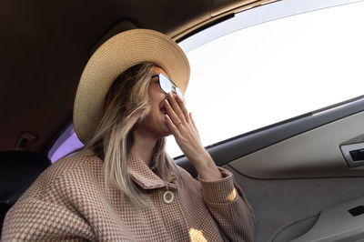 Portrait of woman in car. dressed a coat in a hat and smiling