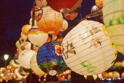 Low angle view of illuminated lanterns hanging against sky at night