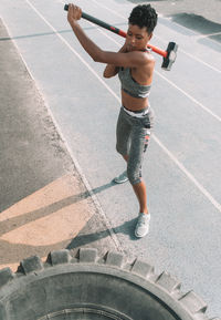 High angle view of woman hammering tire on road