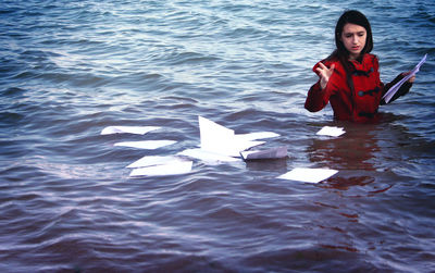 Young woman throwing papers in sea