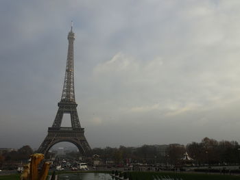 Communications tower in city against cloudy sky