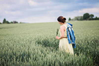 Lifestyle portrait of young stylish woman walking by wheat field