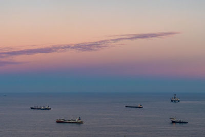 Sailboats on sea against sky during sunset