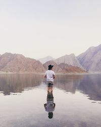 Rear view of man standing in lake against clear sky