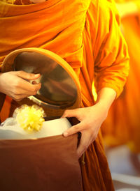 Midsection of monk holding alms