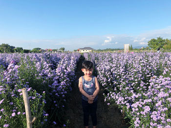 Cute boy standing amidst flowering plants