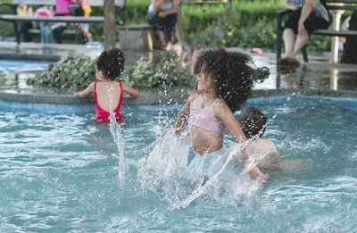 Cheerful girl jumping in swimming pool