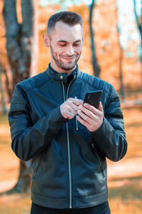 Young man using smart phone while standing outdoors