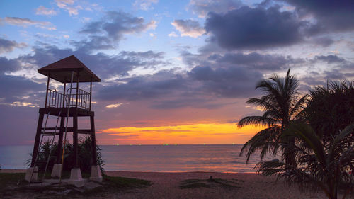 Lifeguard hut on beach against sky during sunset