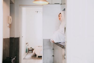 Young woman sitting on door at home