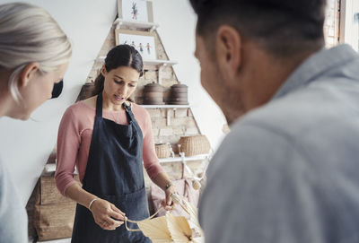 Female owner showing jewelry to customers in store