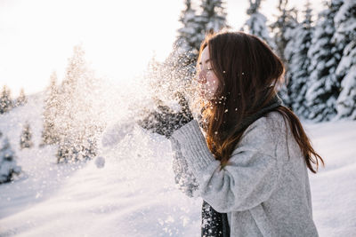 Woman having fun while hiking in the snow during winter, at sunset time.