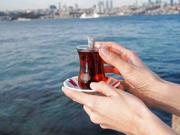 Close-up of hand holding glass of tea in turkey istanbul above of sea