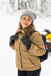 Portrait of smiling young woman standing in snow