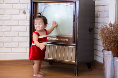 Cute girl standing by vintage television at home