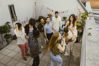 High angle view of carefree male and female friends celebrating together in balcony at party