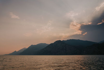 Scenic view of sea and mountains against sky at sunset