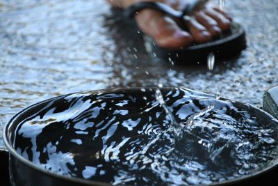 Low section of person wearing flip-flop by container during rainy season